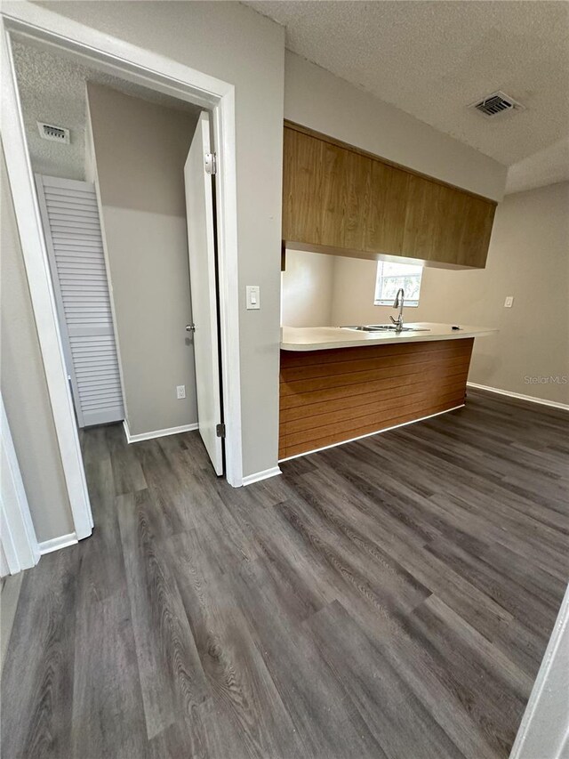 unfurnished living room featuring a textured ceiling, sink, and dark wood-type flooring