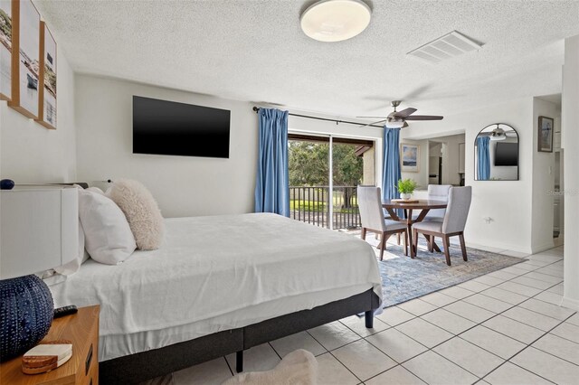 bedroom with ceiling fan, light tile patterned flooring, access to exterior, and a textured ceiling