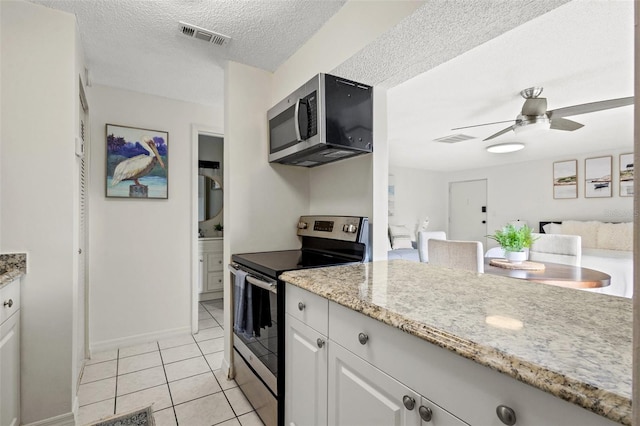 kitchen featuring a textured ceiling, stainless steel appliances, ceiling fan, white cabinetry, and light tile patterned flooring