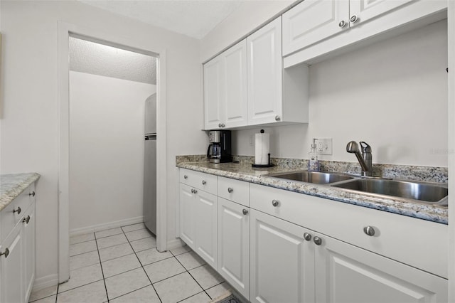 kitchen with sink, stainless steel fridge, a textured ceiling, light tile patterned flooring, and white cabinetry