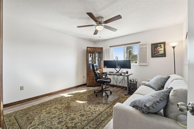 home office featuring ceiling fan, hardwood / wood-style flooring, and a textured ceiling