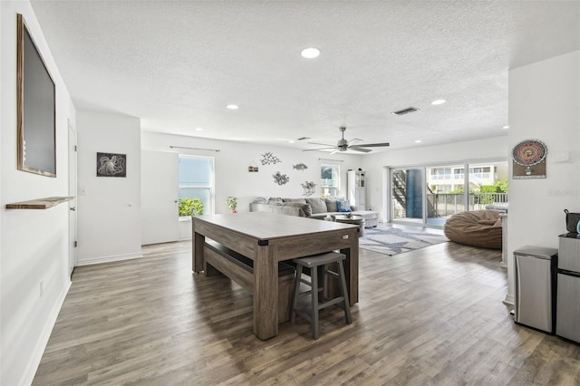 dining area with ceiling fan, a textured ceiling, and hardwood / wood-style floors