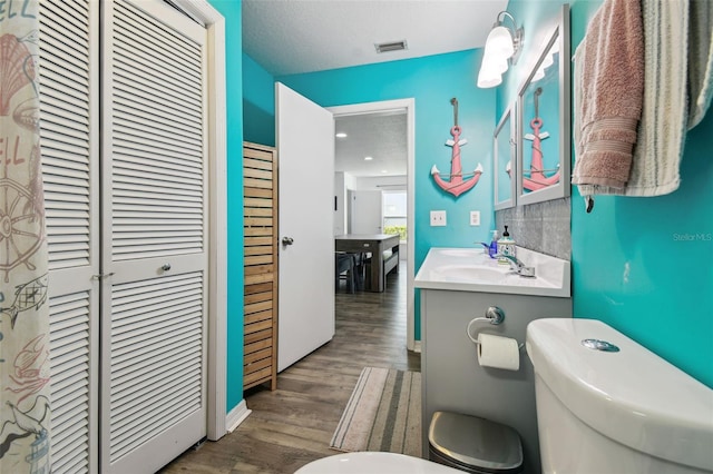 bathroom with vanity, toilet, hardwood / wood-style floors, and a textured ceiling