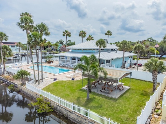 view of swimming pool featuring a water view, a lawn, and a patio