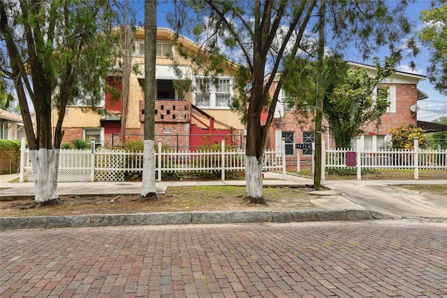 multi unit property featuring stucco siding, a fenced front yard, and brick siding