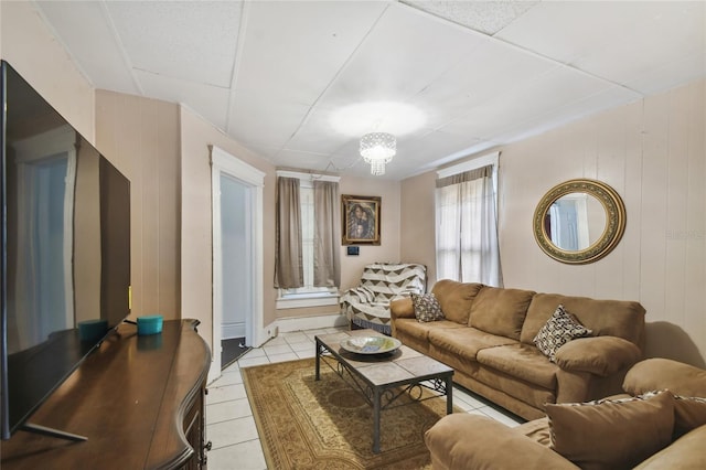 living room with wooden walls, light tile patterned flooring, and a chandelier