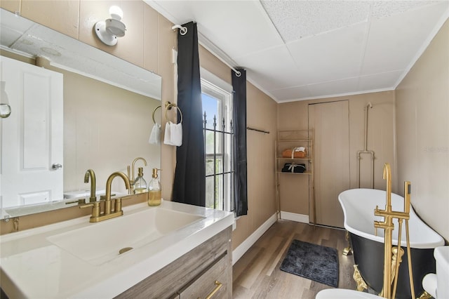 bathroom featuring a freestanding tub, ornamental molding, wood finished floors, and vanity