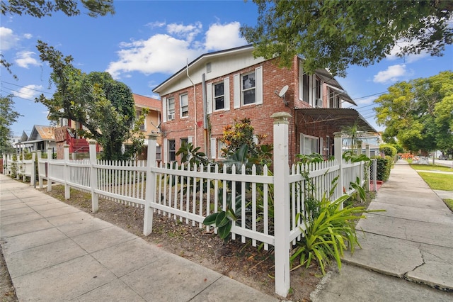 view of front facade with brick siding and a fenced front yard