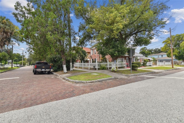 view of property hidden behind natural elements featuring a residential view and fence