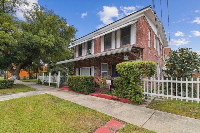 view of property with brick siding, a front yard, and fence