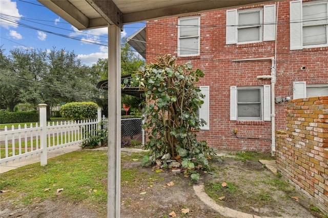 view of side of home featuring brick siding and fence