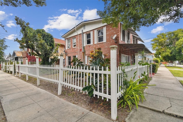 view of front facade featuring brick siding and a fenced front yard