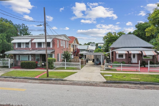 view of property with a fenced front yard, concrete driveway, brick siding, and a carport