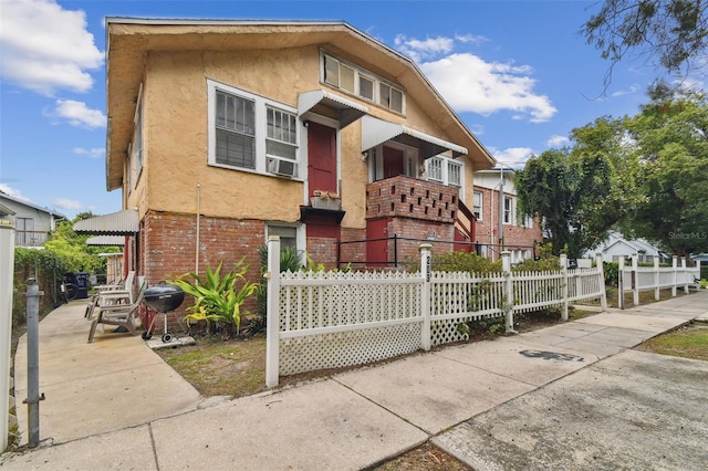 view of front of home featuring brick siding, fence, and stucco siding