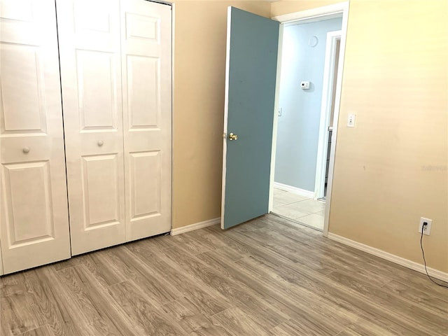 unfurnished bedroom with light hardwood / wood-style flooring and a closet