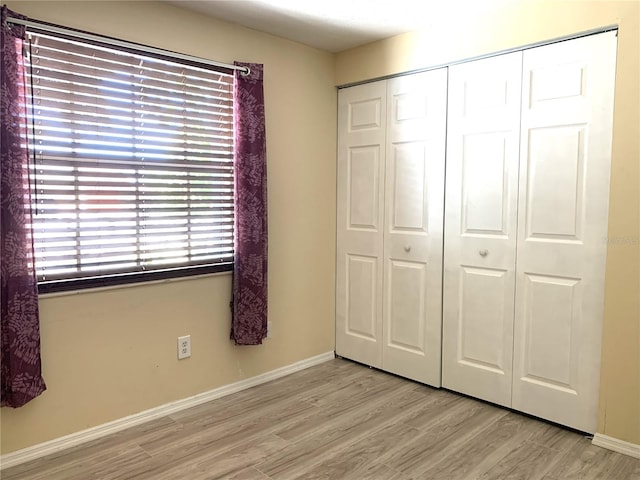 unfurnished bedroom with a closet and light wood-type flooring