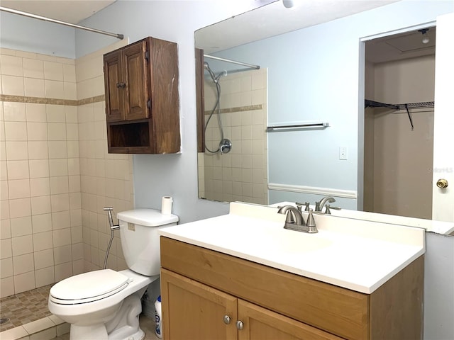 bathroom with a tile shower, tile patterned flooring, vanity, and toilet