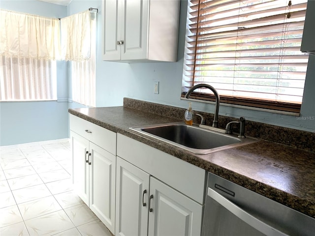 kitchen featuring stainless steel dishwasher, sink, and white cabinets