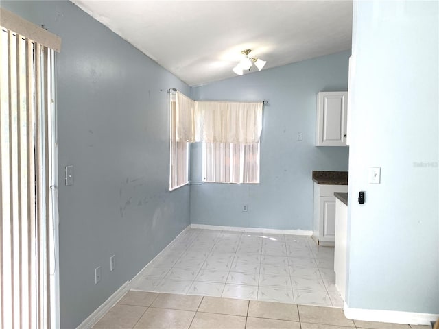 spare room with vaulted ceiling and light tile patterned floors