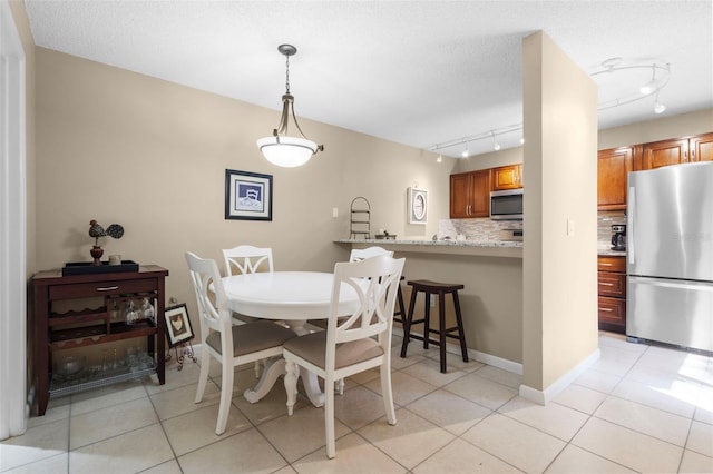 dining space featuring a textured ceiling, light tile patterned floors, and rail lighting