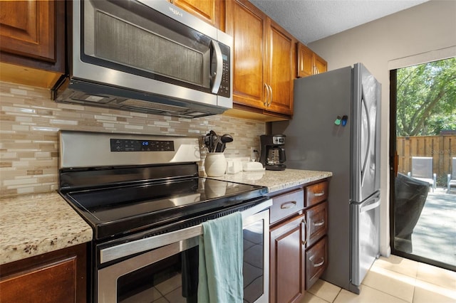 kitchen with stainless steel appliances, backsplash, a textured ceiling, and light tile patterned floors