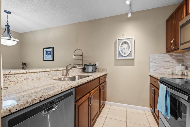 kitchen featuring light stone counters, appliances with stainless steel finishes, decorative light fixtures, and sink