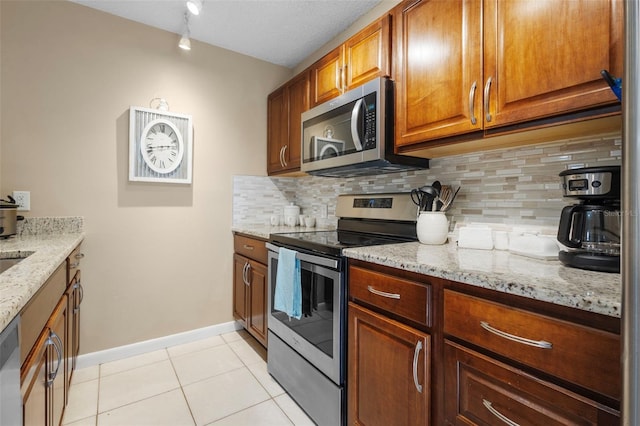 kitchen with appliances with stainless steel finishes, backsplash, a textured ceiling, and light stone counters