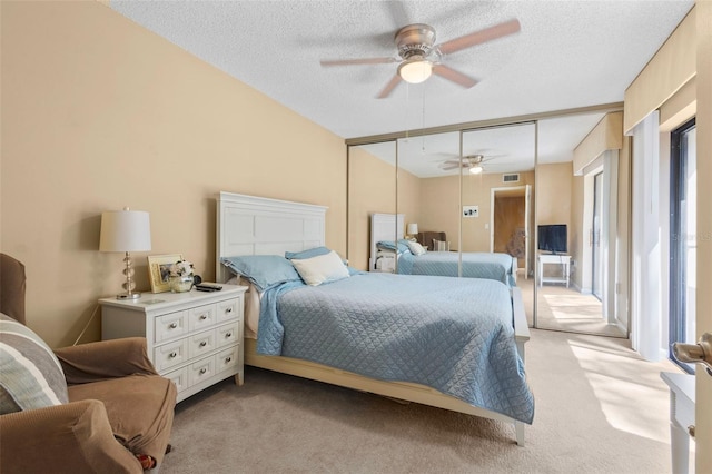 carpeted bedroom featuring a closet, ceiling fan, and a textured ceiling