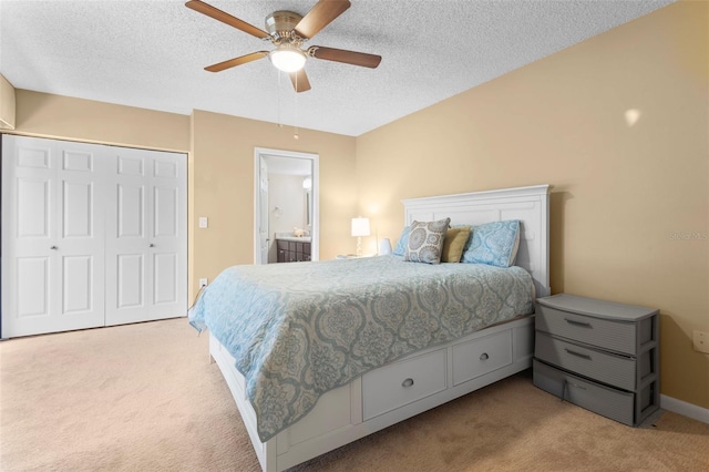 bedroom with connected bathroom, a closet, a textured ceiling, ceiling fan, and light colored carpet