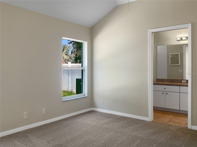 carpeted empty room featuring lofted ceiling