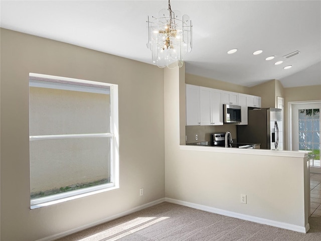 kitchen featuring hanging light fixtures, white cabinetry, stainless steel appliances, a chandelier, and light colored carpet