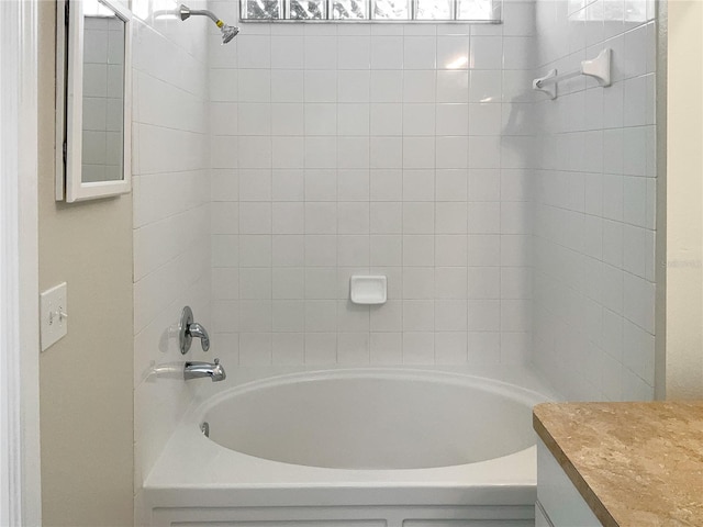 bathroom with tiled shower / bath and vanity