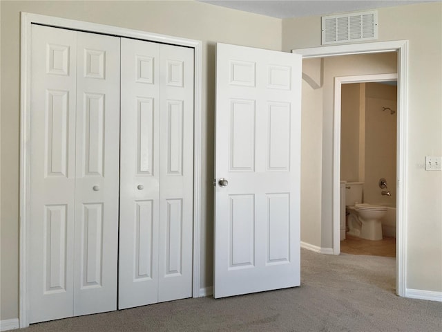 unfurnished bedroom with connected bathroom, light carpet, and a closet