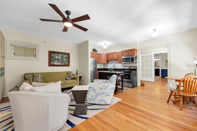 living room with ceiling fan, light hardwood / wood-style flooring, and sink