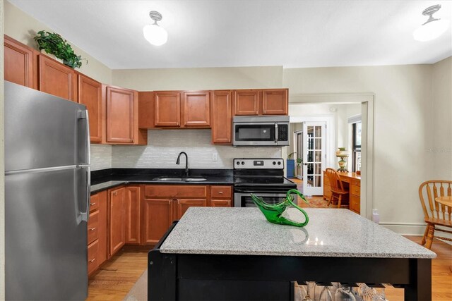 kitchen with stainless steel appliances, backsplash, sink, and light hardwood / wood-style flooring