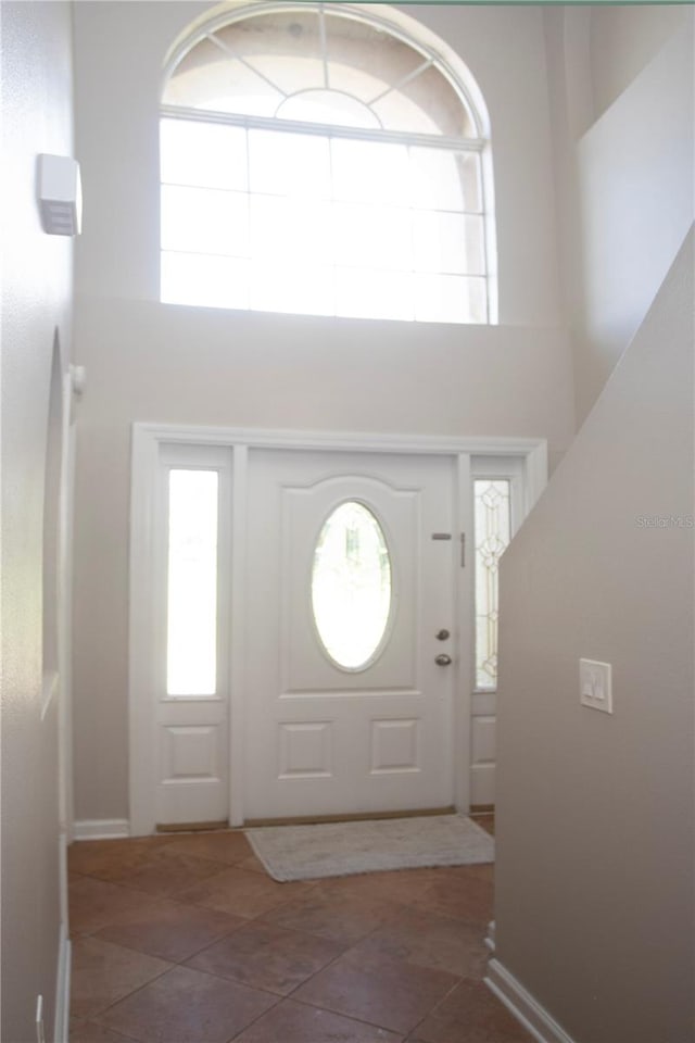 foyer with a high ceiling and dark tile patterned floors