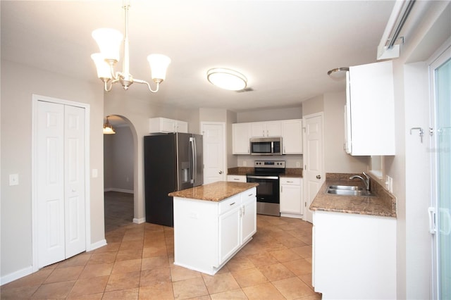 kitchen with visible vents, a kitchen island, appliances with stainless steel finishes, arched walkways, and a sink