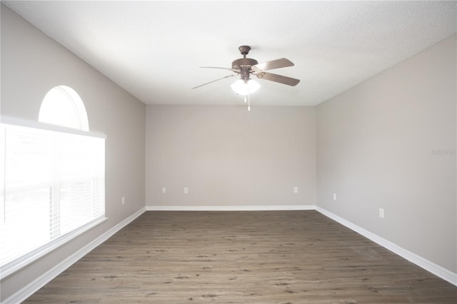 unfurnished room with a wealth of natural light, ceiling fan, and dark hardwood / wood-style flooring