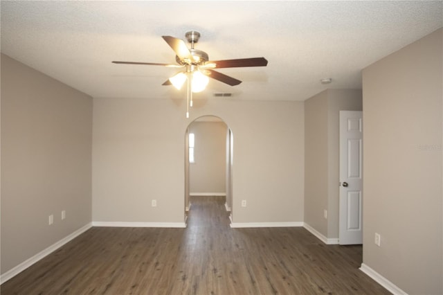 spare room featuring wood finished floors, visible vents, baseboards, arched walkways, and ceiling fan