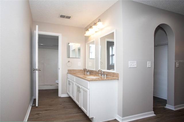 bathroom with wood-type flooring, vanity, toilet, and a textured ceiling