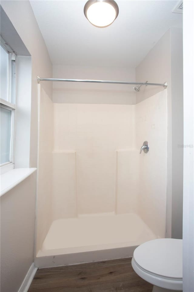 full bathroom featuring toilet, wood finished floors, and walk in shower