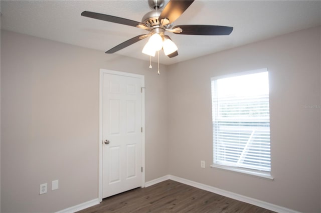 spare room with dark wood finished floors, baseboards, and ceiling fan
