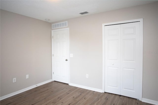 unfurnished bedroom featuring a textured ceiling, dark wood-type flooring, and a closet