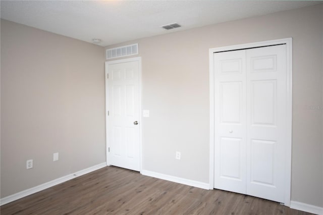 unfurnished bedroom featuring wood finished floors, visible vents, and baseboards