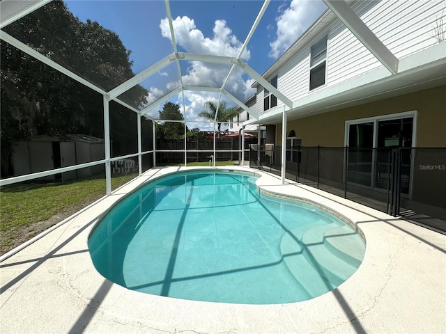 view of pool with a storage shed, a patio, a lanai, and a lawn