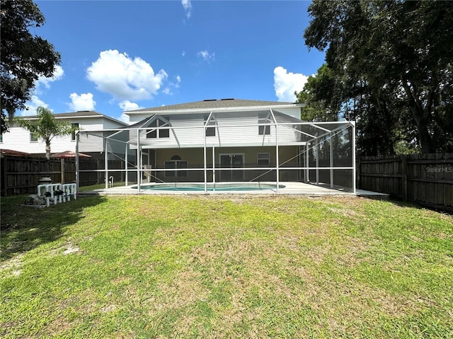 rear view of property featuring a lanai, a fenced in pool, a lawn, and a fenced backyard