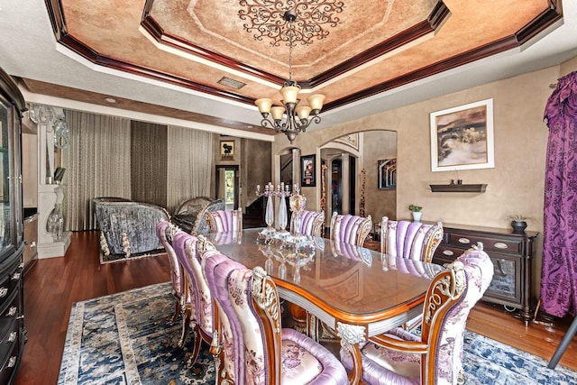 dining space with a raised ceiling, an inviting chandelier, and wood-type flooring