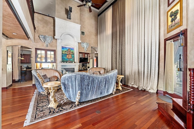 living room featuring ceiling fan, beamed ceiling, a high ceiling, and wood-type flooring