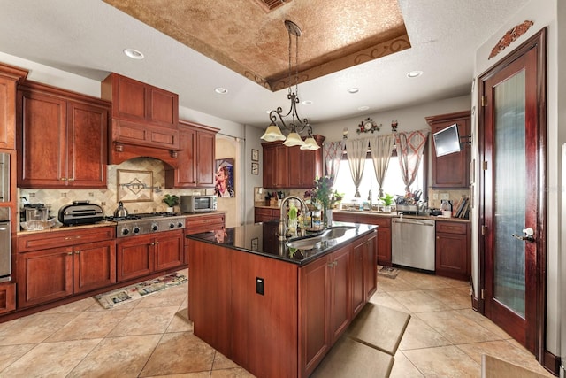 kitchen with a raised ceiling, sink, a textured ceiling, a kitchen island with sink, and stainless steel appliances