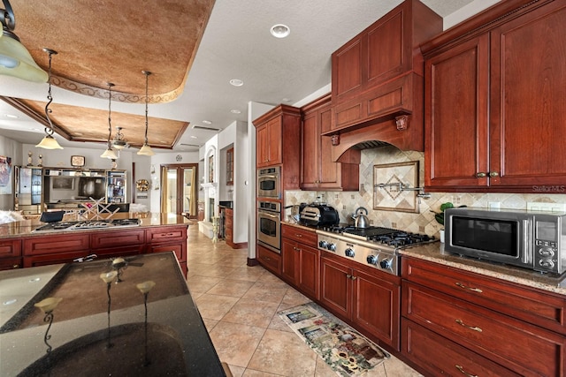 kitchen with dark stone countertops, a raised ceiling, and appliances with stainless steel finishes